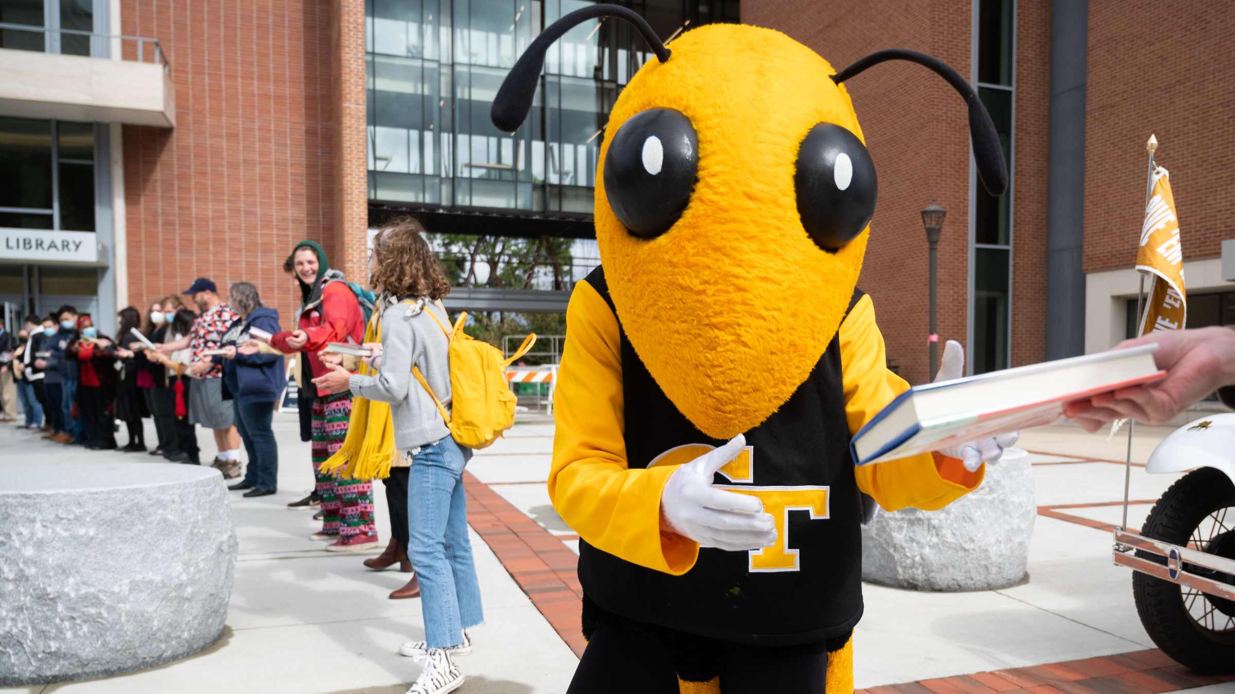 Buzz passing a book in front of the Library