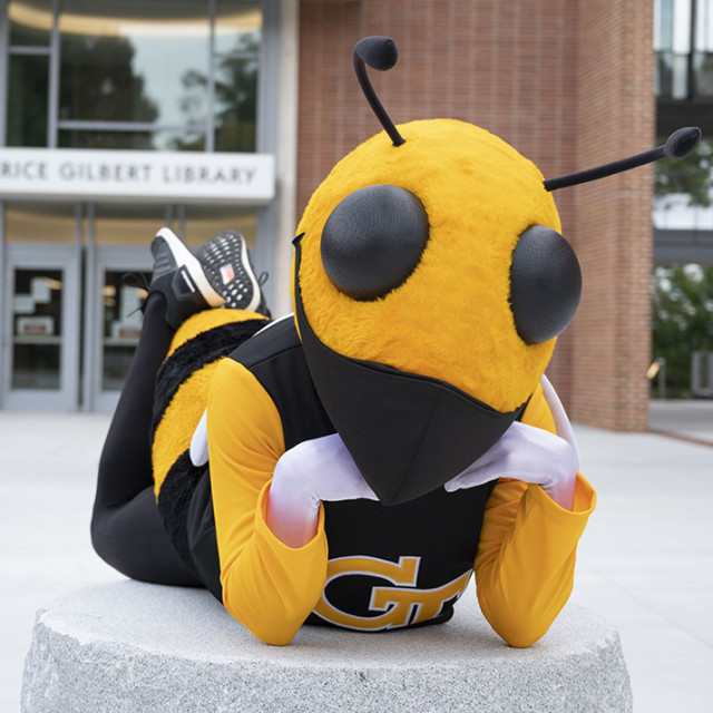 Buzz wearing mask in front of Library